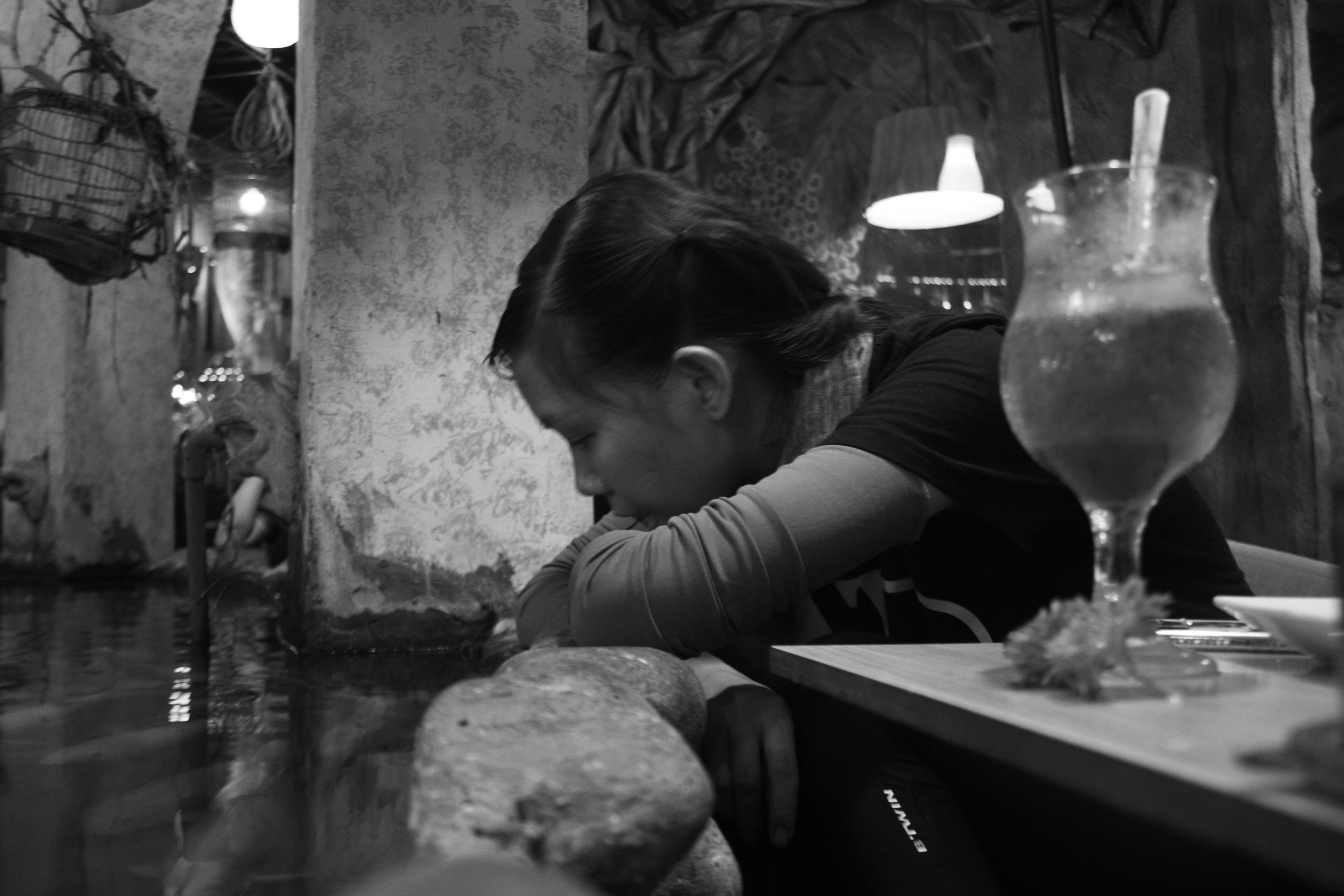 Ein vietnamesisches Mädchen sitzt ruhig im Café und schaut sich den Fisch an.