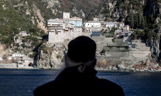 Ein Mönch steht auf einer Fähre und blickt auf das Kloster Dionysiou, eines der 20 Klöster im Athos-Gebirge im Norden Griechenlands. Foto: Guardian