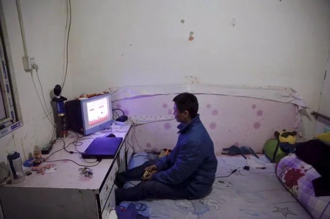 A young man plays video games in a 200 yuan per month rented room. Photo: Udn