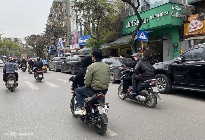 Deux personnes conduisant une moto électrique sans casque circulaient dans la rue Dao Tan, dans le district de Ba Dinh, à midi le 20 mars. Photo : Quynh Nguyen