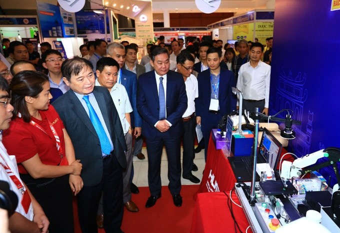 Les délégués visitent le stand présentant les produits technologiques lors de l'événement. Photo : TTTT