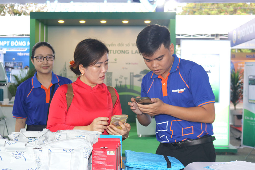 Staff of a bank in the province instruct people on how to use cashless payment services and digital banking applications at Dong Nai Digital Transformation Week 2023. Photo: H. Quan