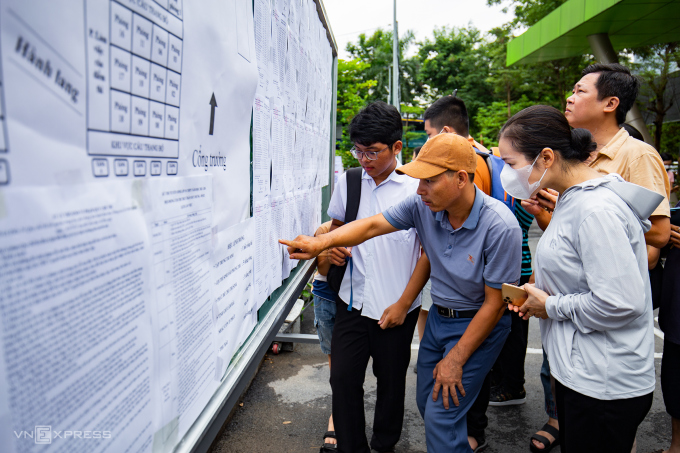 Parents and students in Hanoi look at their registration numbers and exam room diagrams during the 10th grade entrance exam for public high schools, June 2023. Photo: Tung Dinh