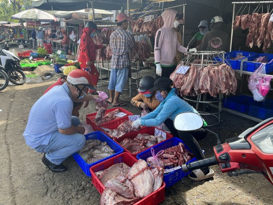 Người mua lựa chọn thịt heo bày đầy trên đường tại một điểm bán tự phát trước cổng chợ đầu mối Hóc Môn trưa 25-11. Ảnh: THI HỒNG