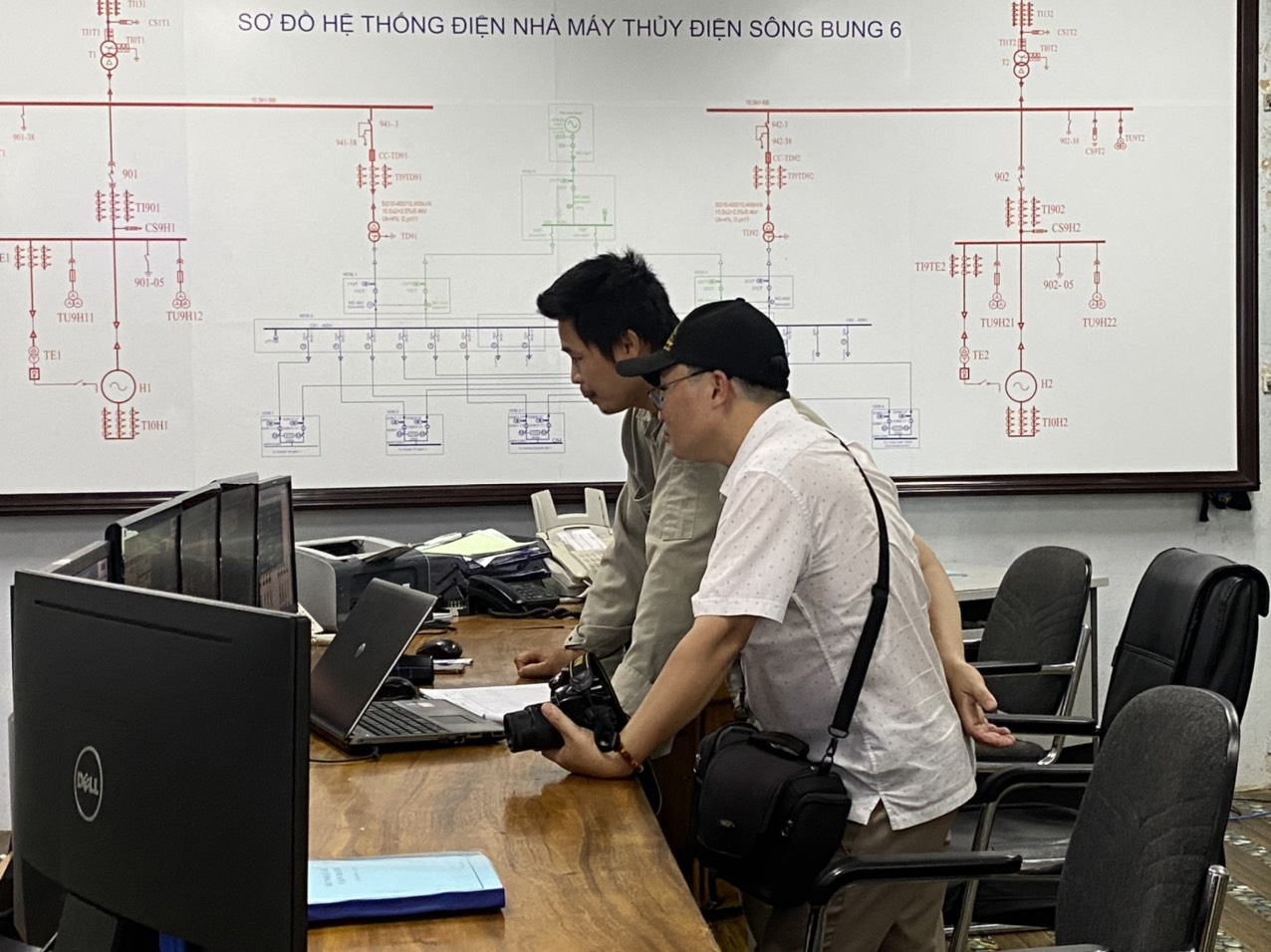 Журналист Ле Хоанг Хиеп (справа) изучает информацию и работу гидроэлектростанции.