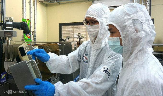 Deux étudiants vietnamiens utilisent une machine de moulage de puces semi-conductrices dans la salle de pratique de l'Université Minh Tan. Photo : Le Nguyen