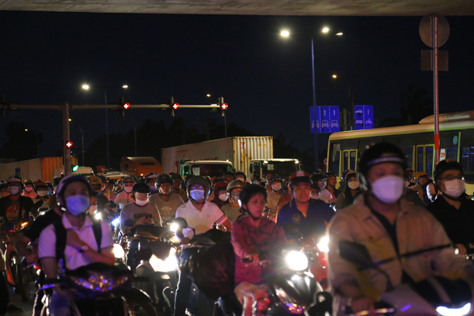 Las motos se empujan unas a otras mientras circulan de noche por la rotonda de My Thuy, junto a una hilera de tractocamiones. Foto: Dinh Van