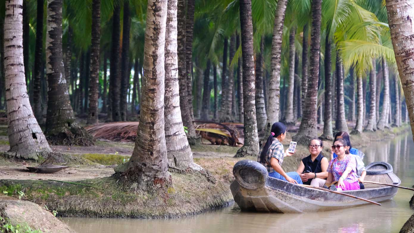 Tourists enjoy rowing down to visit the coconut garden. Photo: My Ly