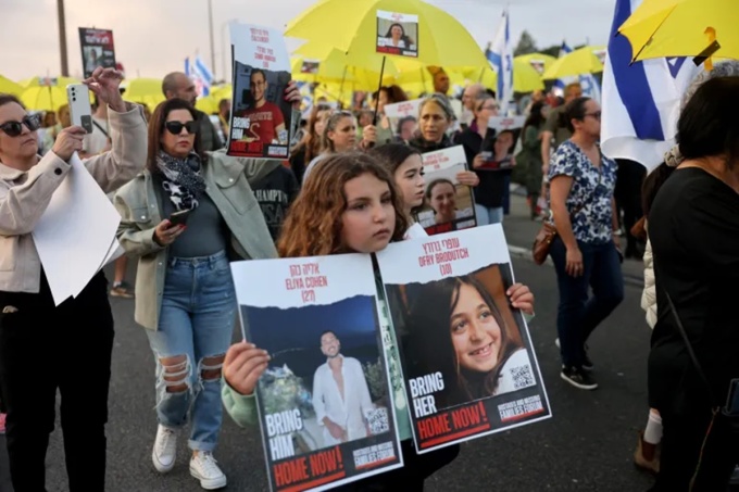 Une fille porte une photo d'Eliya Cohen, 27 ans (à gauche) et d'Ofry Brodutch, 10 ans, deux otages détenus par le Hamas à Gaza, lors d'une marche le 18 novembre. Photo : AFP