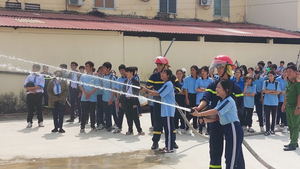 Students practice spraying water to put out a fire. Photo by Xuan Luong