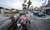 Marée haute, les habitants de Ho Chi Minh-Ville peinent à traverser l'eau pour rentrer chez eux