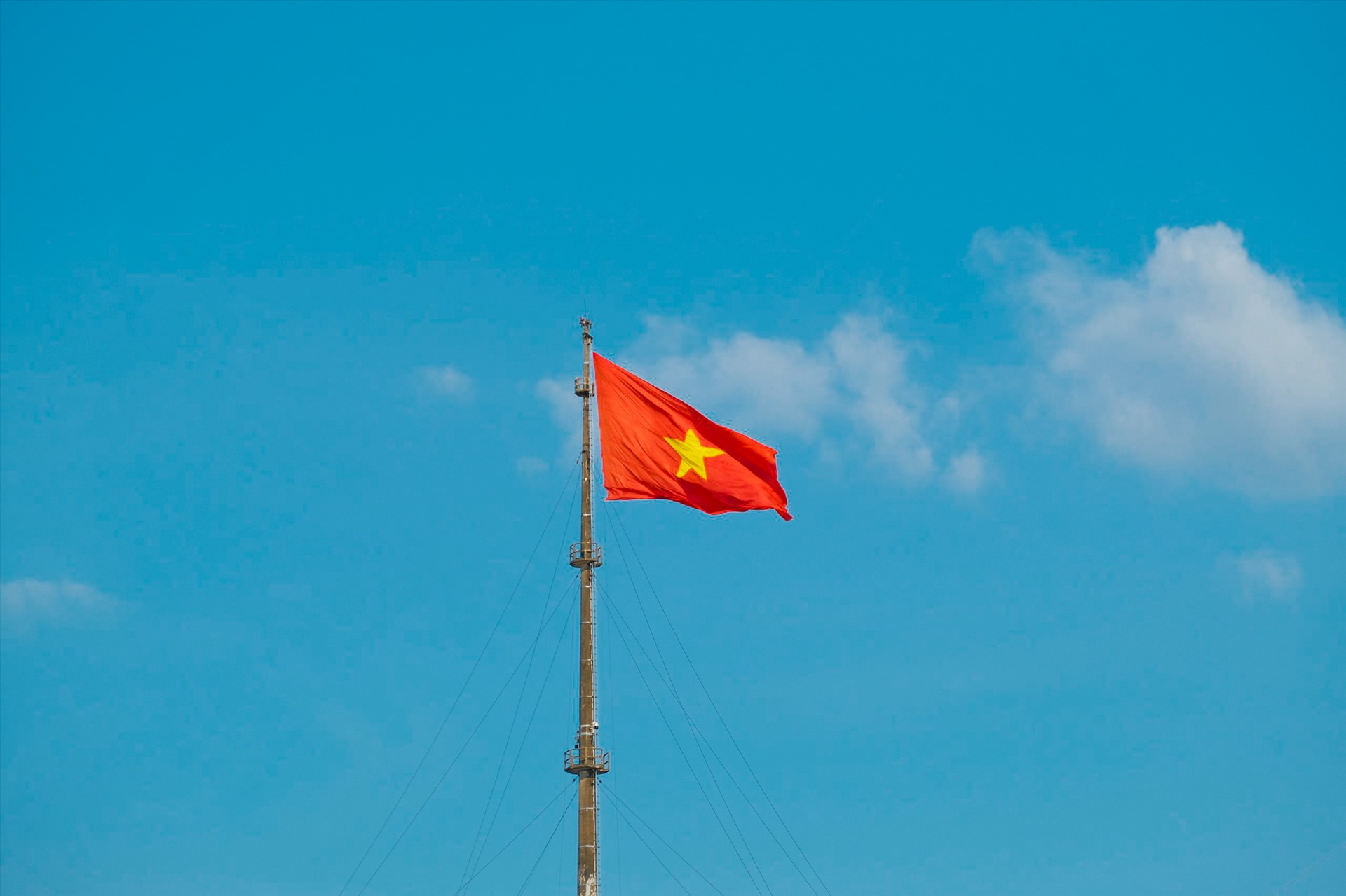 The red flag with yellow star flutters on top of the flagpole, showing national pride and spirit.