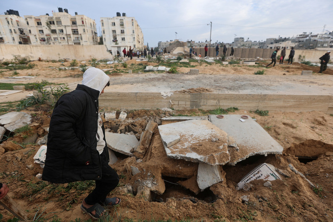 Người đàn ông kiểm tra các ngôi mộ bị phá hủy trong nghĩa trang ở thành phố Khan Younis, nam Gaza ngày 17/1. Ảnh: Reuters