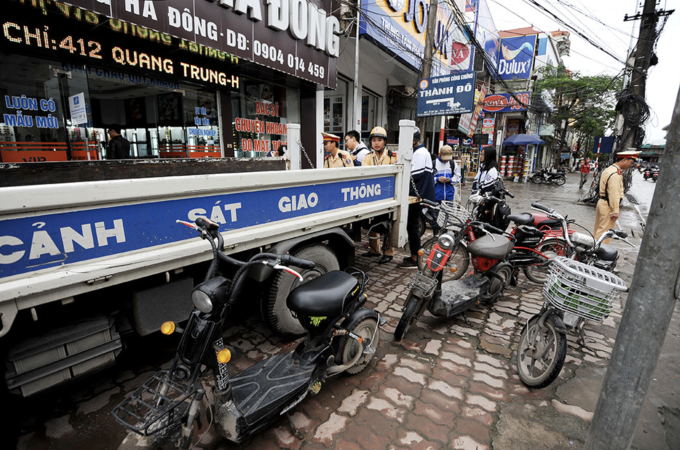 La policía de tráfico de Hanoi multó a los estudiantes que circulaban en motocicletas y bicicletas eléctricas sin casco. Foto: Giang Huy