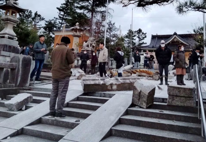 Người dân đứng gần cổng torii bị sập do động đất tại đền Onohiyoshi ở Kanazawa, tỉnh Ishikawa ngày 1/1. Ảnh: Reuters