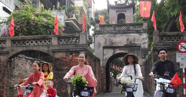 Des centaines de personnes portant l'Ao Dai, parcourent à vélo les rues de Hanoi