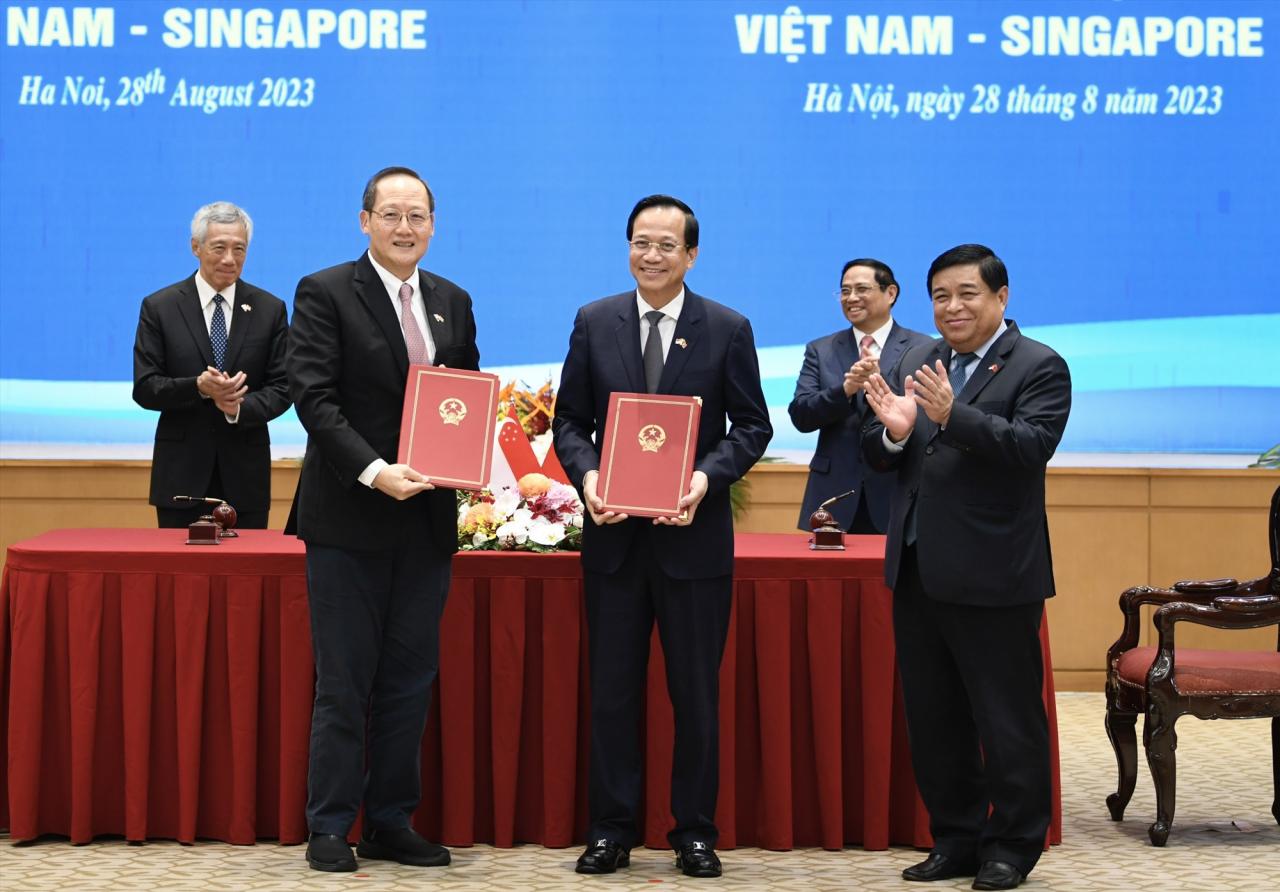 De droite à gauche : le ministre de la Main-d'œuvre et deuxième ministre de l'Industrie et du Commerce Tan See Leng, le ministre du Travail, des Invalides et des Affaires sociales Dao Ngoc Dung et le ministre de la Planification et de l'Investissement Nguyen Chi Dung signent le protocole d'accord. Photo : Hai Nguyen