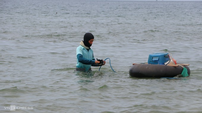 Mr. Mai Van Lam pushes the buoy and diving machine out to Mui Ne beach, preparing to dive for clams. Photo: Tu Huynh