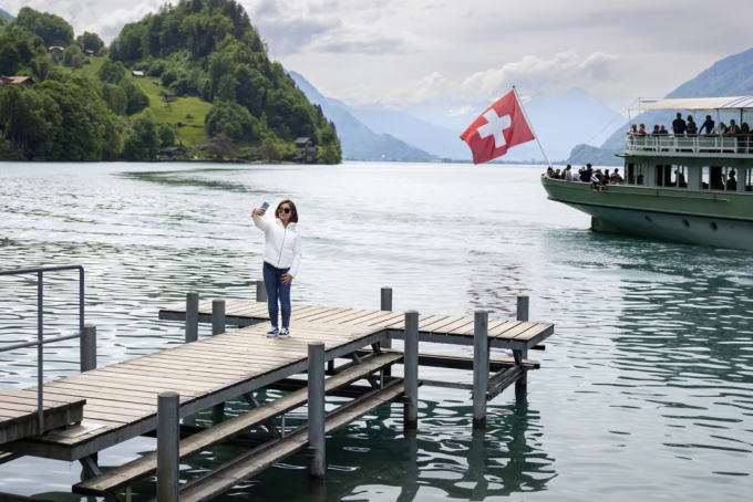 นักท่องเที่ยวชาวจีนถ่ายรูปบริเวณท่าเทียบเรือที่ใช้เป็นสถานที่ถ่ายทำภาพยนตร์เรื่อง Crash Landing on You ในระยะไกลเธอเห็นเรือสำราญที่เต็มไปด้วยผู้โดยสารกำลังจะจอดเทียบท่า ภาพ: EPA