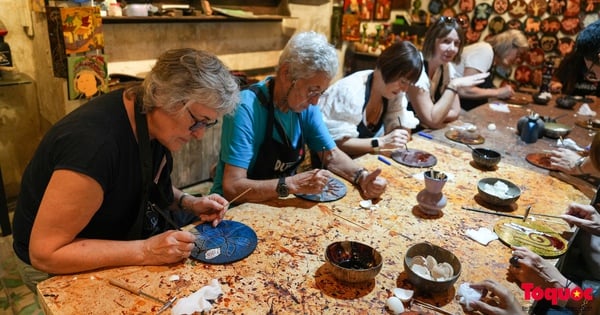 Les touristes étrangers profitent de l'expérience de la réalisation de peintures à la laque