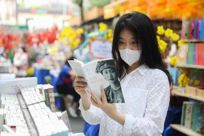 Une étudiante lit un livre d'histoire sur la reine Nam Phuong dans la rue du livre Nguyen Van Binh, en 2022. Photo : Quynh Tran