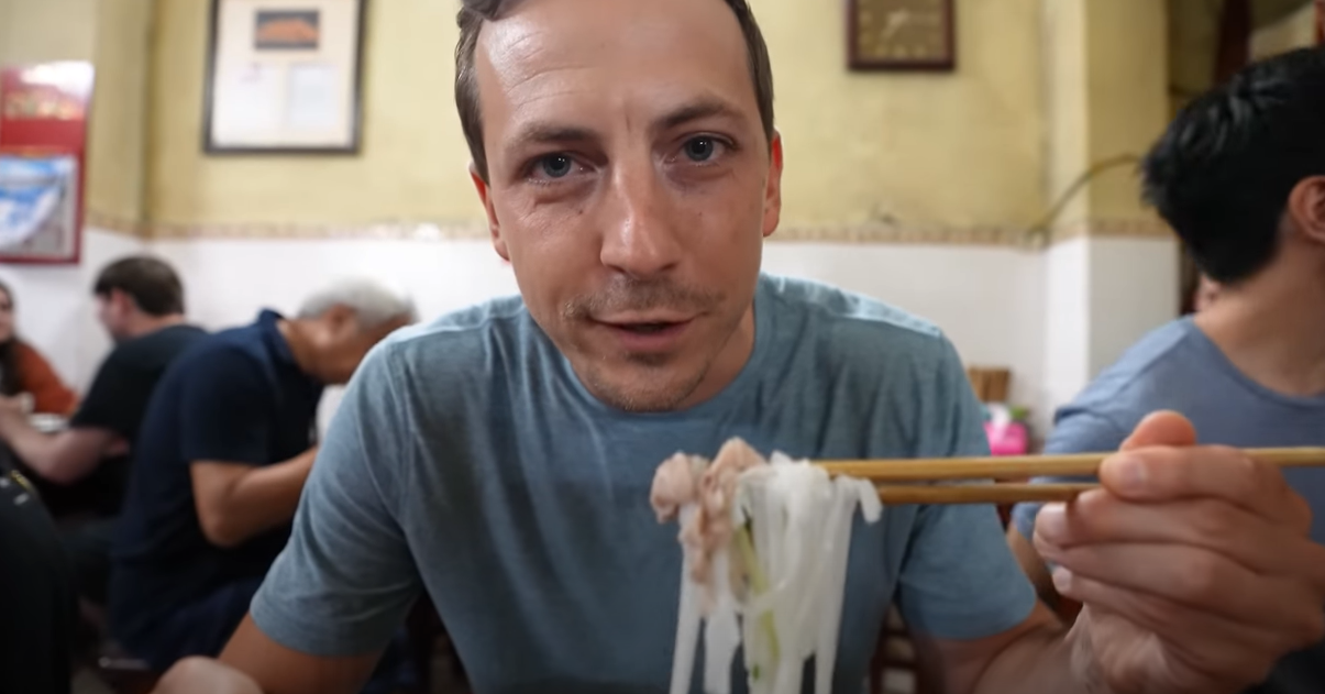 Westliche Touristen probieren traditionelle Pho in Hanoi, loben es als köstlich, schlürfen die ganze Brühe