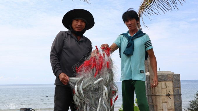 นาย Truong Quang Tan (ซ้าย) และหุ้นส่วนชาวประมงนำปลาที่เพิ่งจับได้ขึ้นฝั่งที่หมู่บ้านชาวประมง Mui Ne เมือง Phan Thiet ภาพโดย Viet Quoc