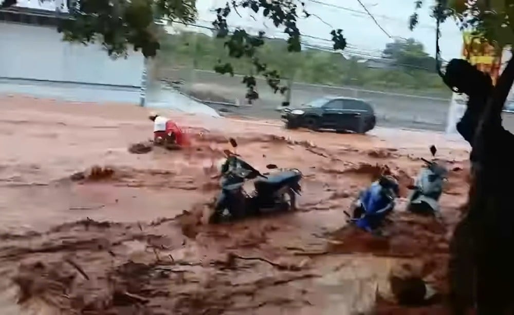 Les inondations de sable continuent de dévaler les rues de la ville de Phan Thiet, emportant une fille sur une moto.jpg