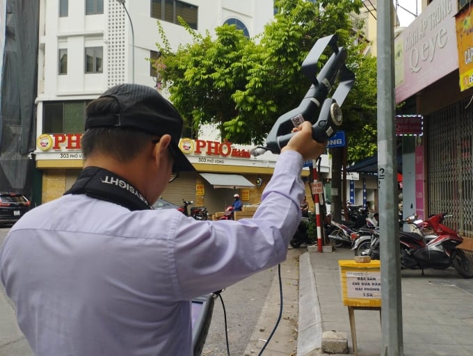 Cán bộ Cục Tần số vô tuyến điện dùng thiết bị kiểm tra ở phố Vọng, chiều 22/6. Ảnh:Việt An