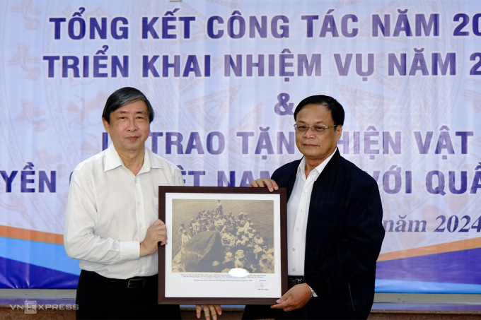 El Sr. Bui Van Tieng, presidente de la Asociación de Ciencias Históricas de la ciudad de Da Nang (derecha), presentó evidencia fotográfica de Hoang Sa de Vietnam al Sr. Vo Ngoc Dong, presidente del Comité Popular del distrito de Hoang Sa. Foto: Nguyen Dong