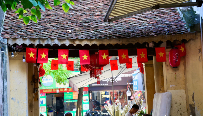 La bandera roja con estrella amarilla está colgada de forma brillante en la puerta del pueblo, en medio de las calles de Hanoi.