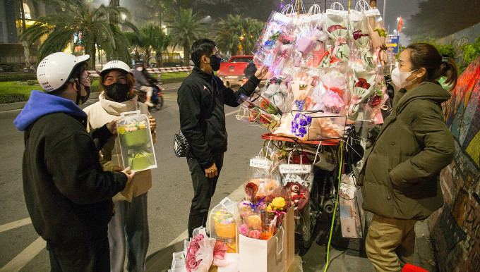 Some customers come to see handmade woolen flower bouquets at a cart on Yen Phu Street, Tay Ho District, on the evening of March 4. Photo: Thanh Nga