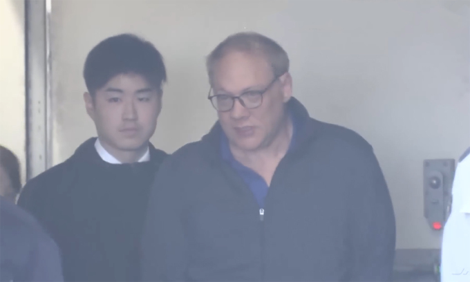 客室乗務員（左から2人目）を噛んだアメリカ人男性が1月16日、日本の空港で護送されている。写真：TBS