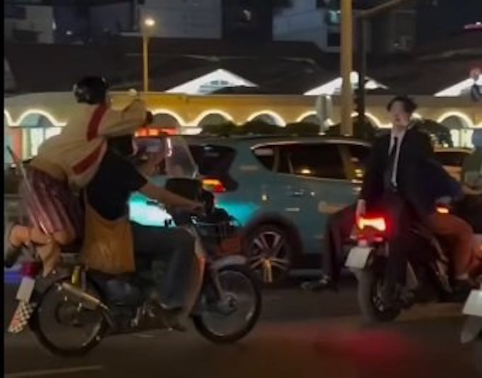 Un joven con chaleco sin casco permite que alguien se suba al asiento de una motocicleta para grabar un video frente al mercado de Ben Thanh, Distrito 1. Foto: Proporcionada por la policía.