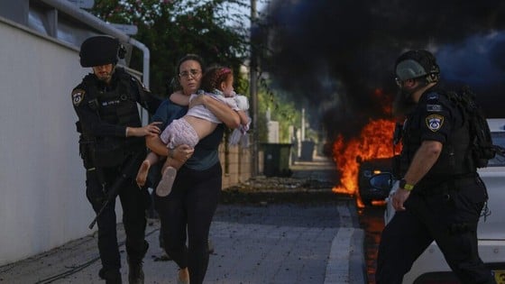 Police carry a woman and her child away from an area hit by rockets in the Gaza Strip on October 7. (Source: AP)