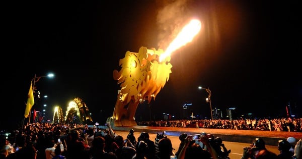 Les gens se baignent sous la pluie et regardent le pont du Dragon cracher du feu pour accueillir la nouvelle année 2024