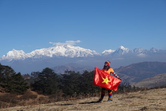 Mme Trang tient le drapeau vietnamien au sommet de Phalut (Inde).