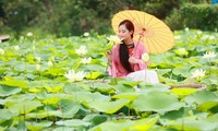 Young people wearing Ao Dai take photos next to white lotus flowers