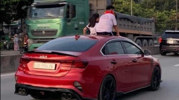 高速道路を走る車の屋根の上に子供を座らせるのは、人命を弄ぶ行為である。