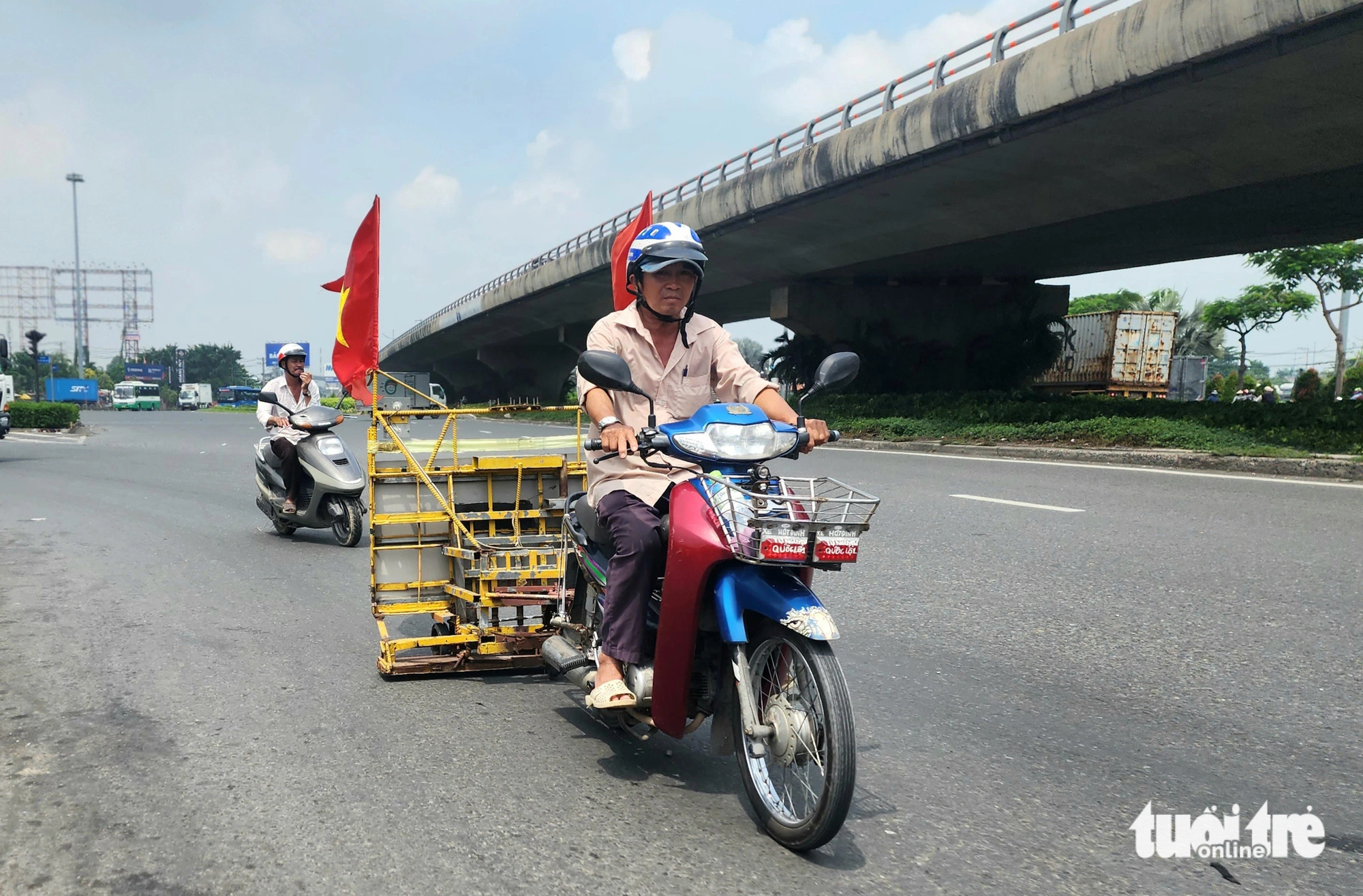 Ông Đinh Minh Cảnh kéo xe hút đinh và vật sắc nhọn trên quốc lộ 1 (gần đoạn giao với đường Nguyễn Văn Linh, huyện Bình Chánh) vào trưa 27-6 - Ảnh: NGỌC KHẢI