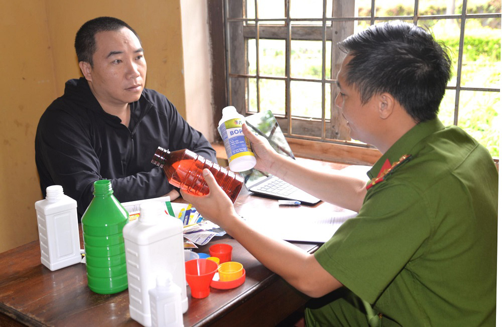 Bị can Nguyễn Thái Học cùng tang vật là các chai lọ dùng chiết thuốc trừ sâu, thuốc diệt cỏ giả - Ảnh: Công an tỉnh Gia Lai 