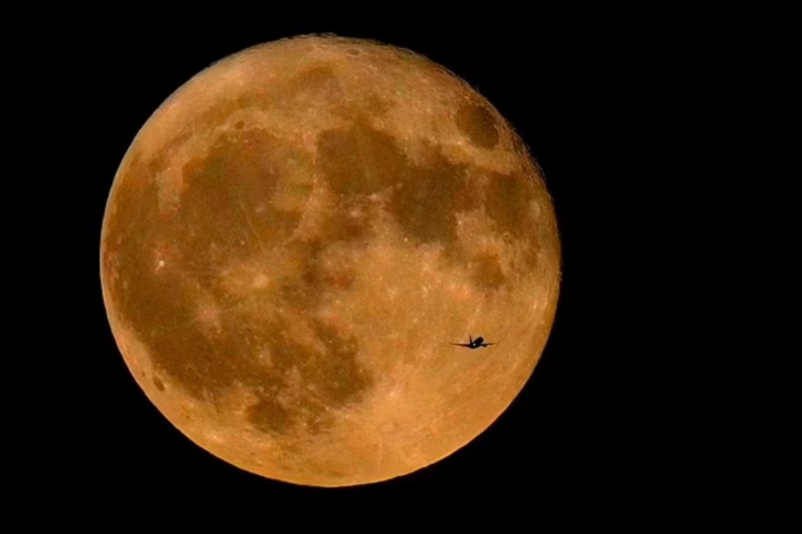 Un avión comercial sobrevuela el lago Michigan antes de la superluna de julio de 2023, la primera de cuatro superlunas en 2023. (Foto: AP)