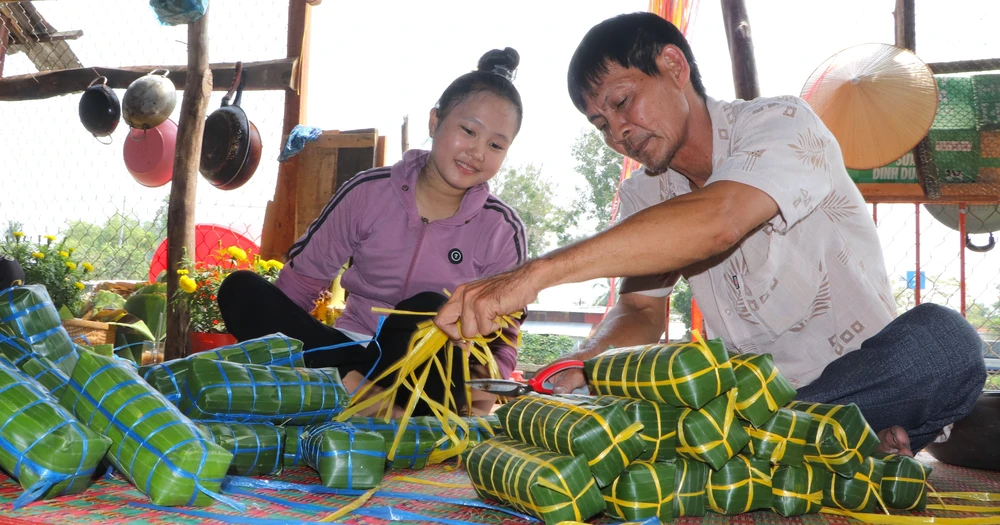 Không khí sum vầy của ngày Tết trong dịp gói bánh tét. (Ảnh: Nguyễn Hằng/TTXVN)