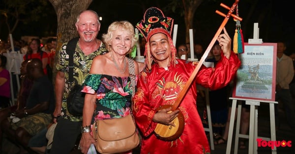 Los turistas extranjeros disfrutan escuchando el canto de Then y la interpretación del laúd de Tinh en la calle peatonal del lago Hoan Kiem.