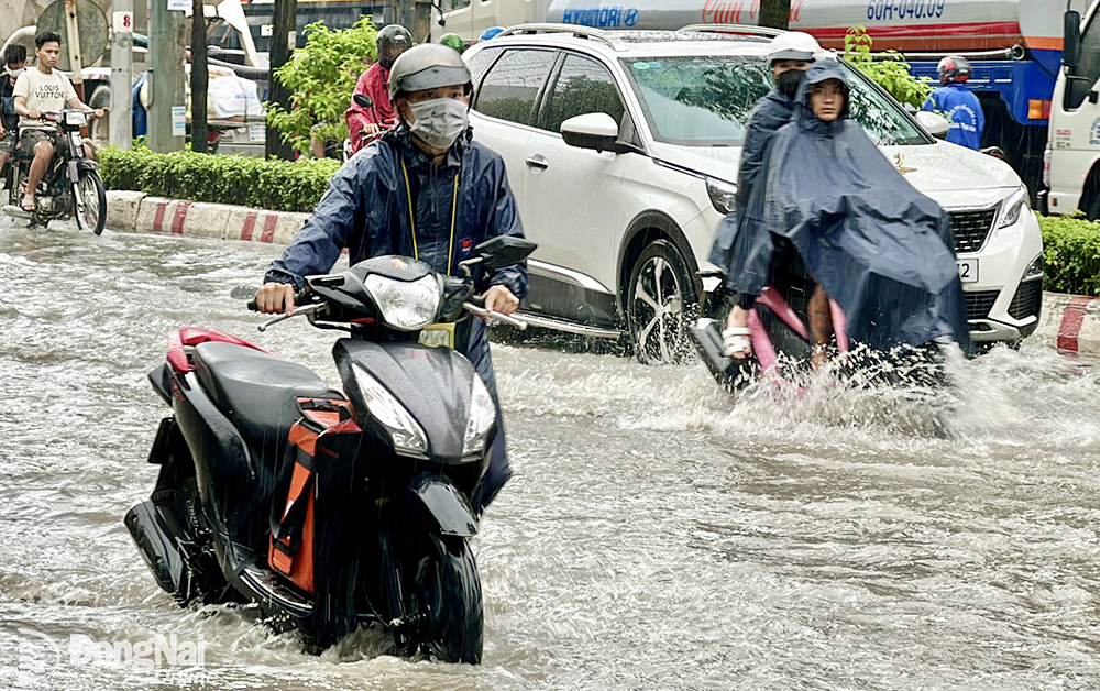 Người và xe di chuyển qua điểm ngập tại ngã ba Trảng Dài. Ảnh: Đăng Tùng