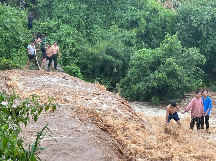 Ba cháu bé bị mắc kẹt giữa dòng nước chảy xiết. (Ảnh: Đ.N)
