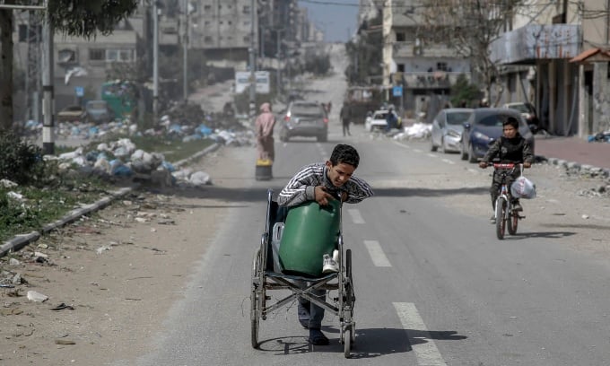 Un niño usa una silla de ruedas para transportar agua en la ciudad de Gaza el 3 de marzo. Foto: AFP