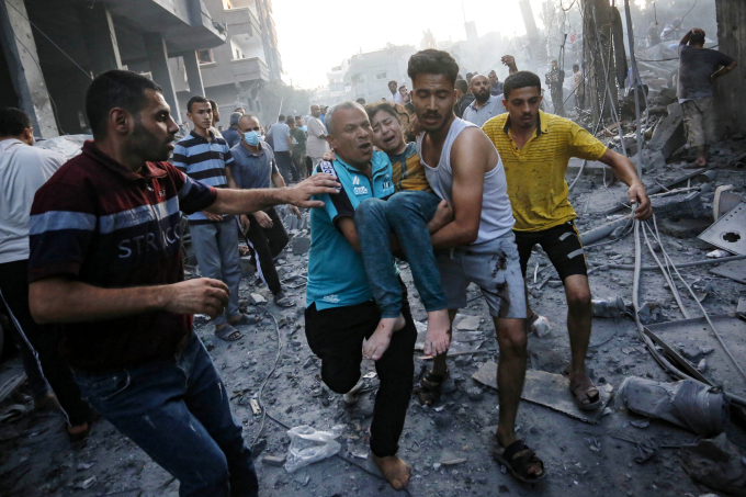Un groupe de personnes déplace une fillette blessée après un raid israélien dans la bande de Gaza le 18 octobre. Photo : AFP