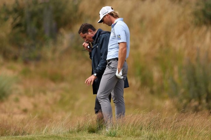 Burns et l'arbitre étudient la situation du ballon coincé sur le bord du piège à sable. Photo : Golf Digest