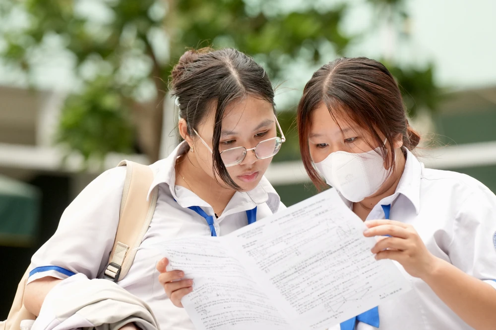 Los candidatos intercambian preguntas del examen de matemáticas después de salir de la sala de exámenes, en el sitio de exámenes de la Escuela Secundaria Colette, Distrito 3, en la tarde del 27 de junio. Foto: HOANG HUNG